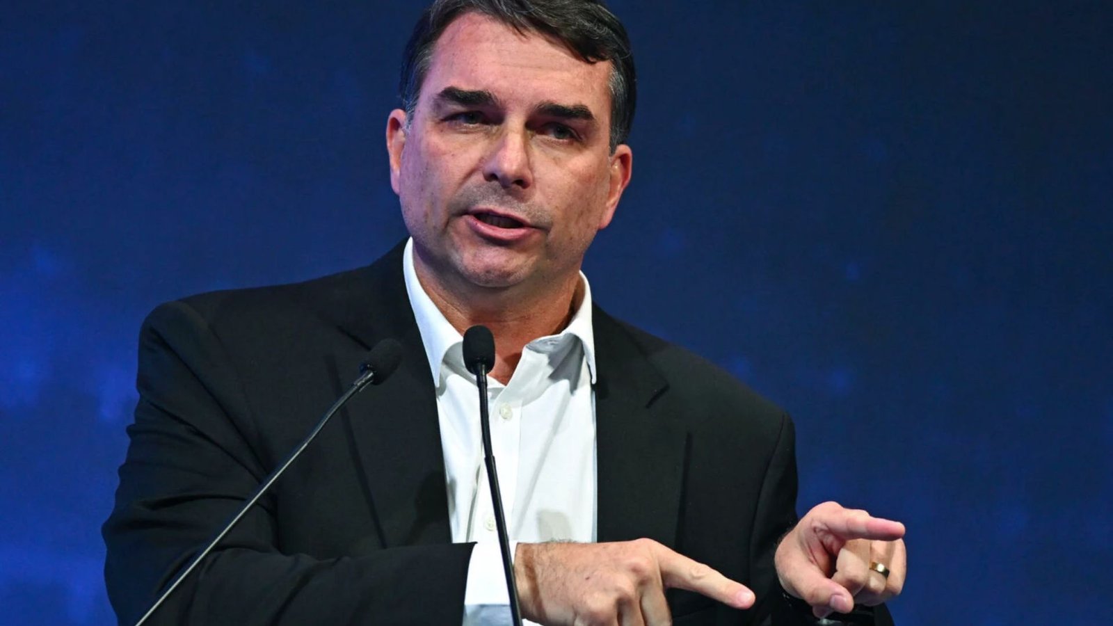 Ao centro, Flávio Bolsonaro de terno preto e camisa social branca. Foram vazados audios de negociações entre e Vorcaro sobre Dark Horse.